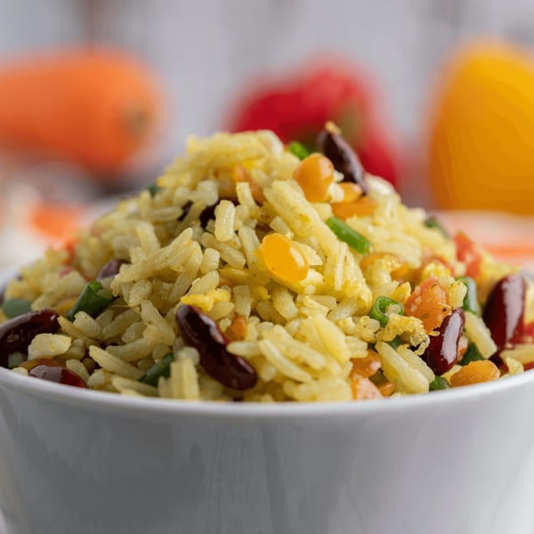 Close-up of Mexican rice with corn, beans, and vegetables in a white bowl.