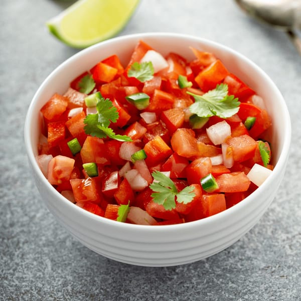 Freshly made pico de gallo with diced tomatoes, onions, cilantro, and jalapeños in a white bowl.