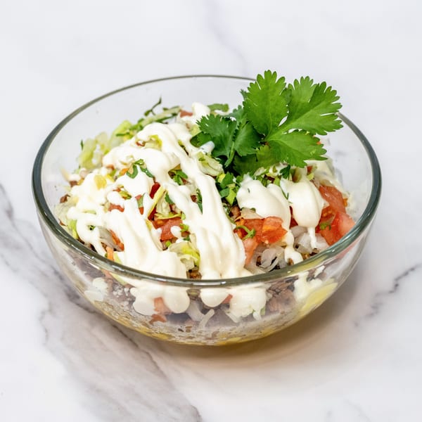 Olivo Taco's Mexican taco bowl with meat, lettuce, tomatoes, onions, cilantro, and crema.